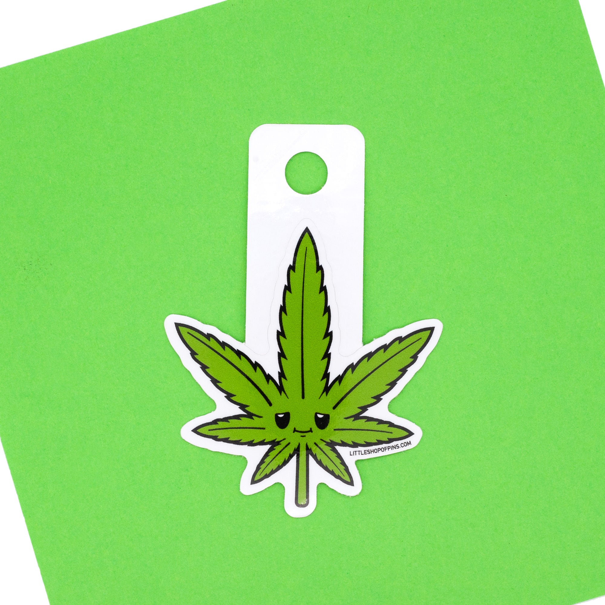 smiling pot leaf vinyl sticker. shot over green background.