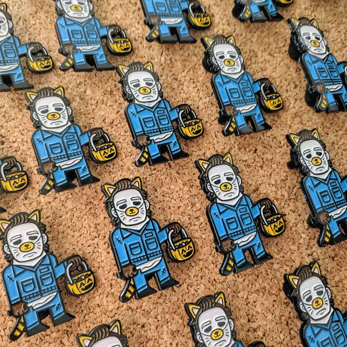 Multiple Michael Myers enamel pins on a cork board.